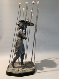 A patinated iron figure of a lady with an umbrella walking through the rain, 20th C.