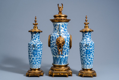 A Chinese three-piece gilt brass mounted clock garniture with blue and white vases with floral design, 19th C.
