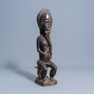 A wooden male figure on a throne, Baule, Ivory Coast, 20th C.