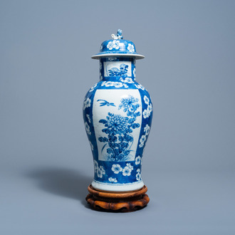 A Chinese blue and white prunus on cracked ice ground vase and cover with floral design on a wood stand, 19th C.