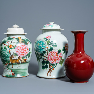 A pair of Chinese famille rose vases and covers with floral design and a monochrome red vase, 19th/20th C.