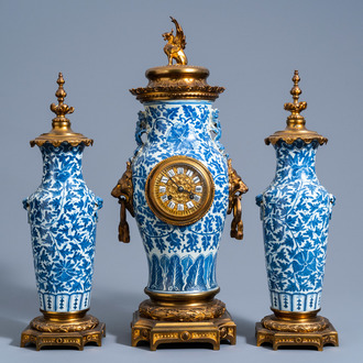 Une garniture du cheminée en trois pièces en porcelaine de Chine bleu et blanc à décor floral et aux montures en cuivre doré, 19ème siècle