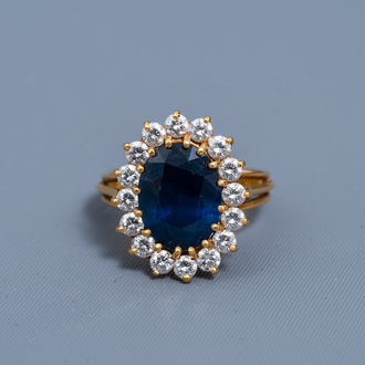 An 18 carat yellow gold ring set with a blue sapphire and sixteen diamonds, 20th C.