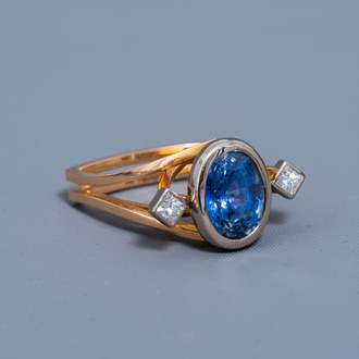 An 18 carat yellow and white gold ring set with a blue sapphire and two diamonds, 20th C.